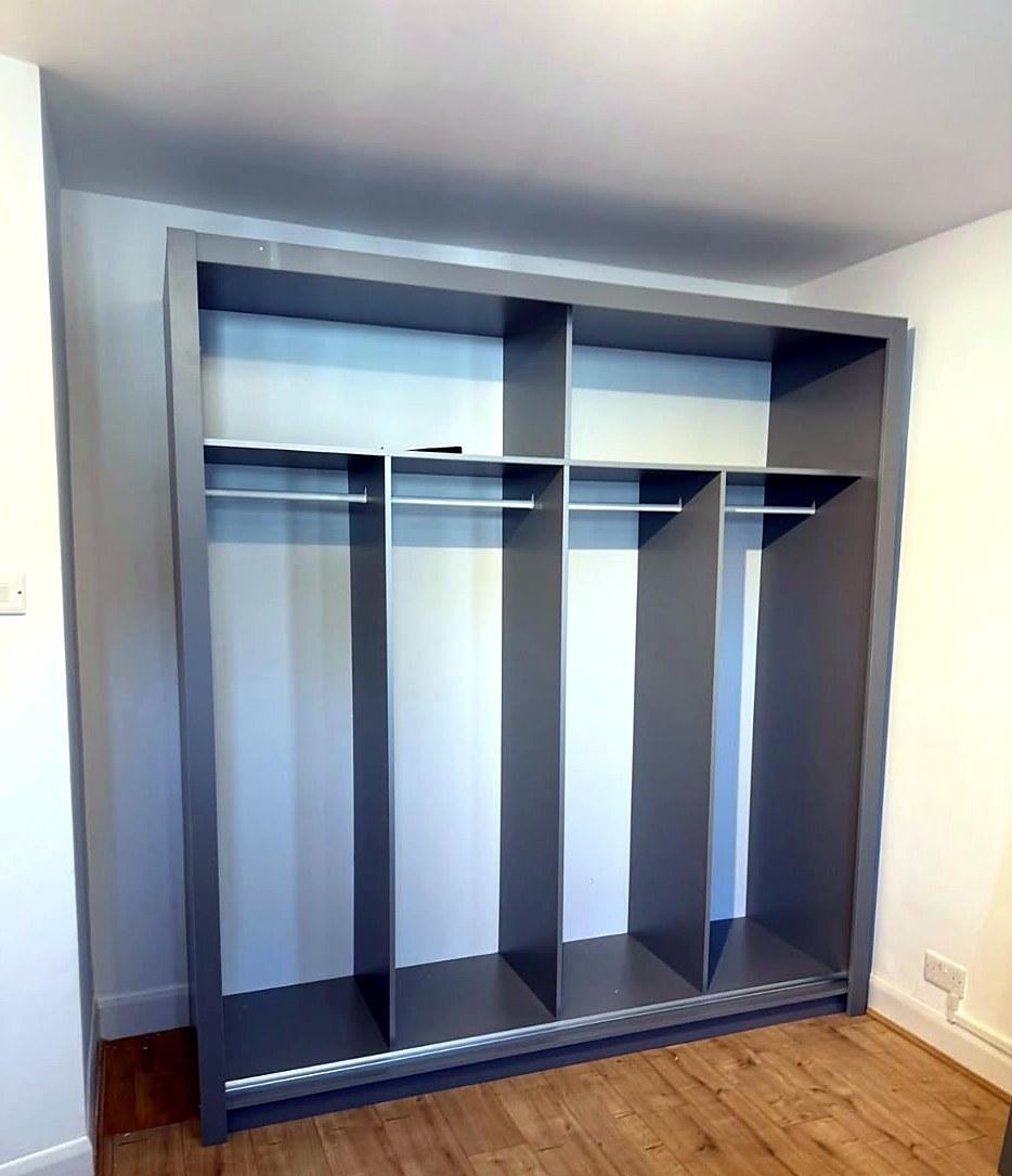 Interior of a grey sliding-door wardrobe, assembled, with shelves and hanging rails