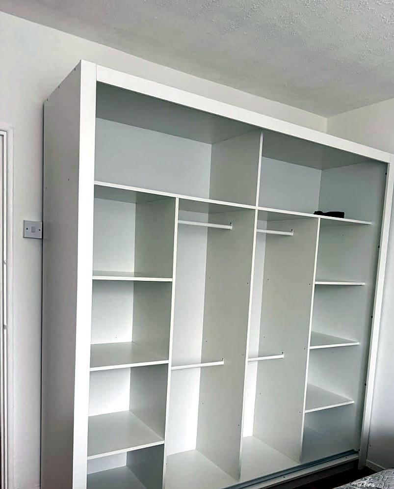 Interior of a white sliding-door wardrobe, assembled, with shelves and hanging rails