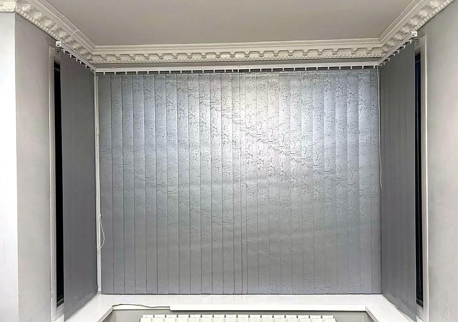 Grey vertical blinds fitted around a bay window with a coved ceiling