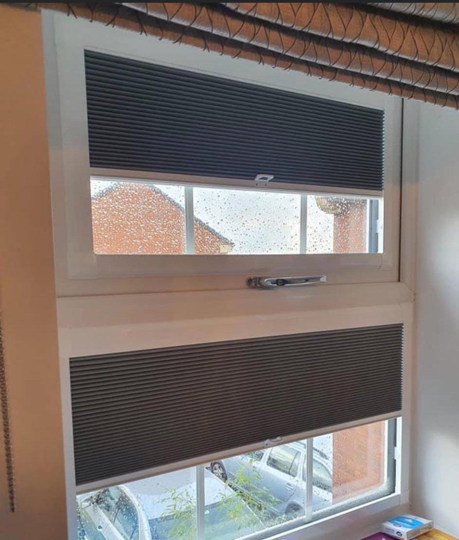 Charcoal honeycomb pleated blinds fitted to the top and bottom panes of a bedroom window