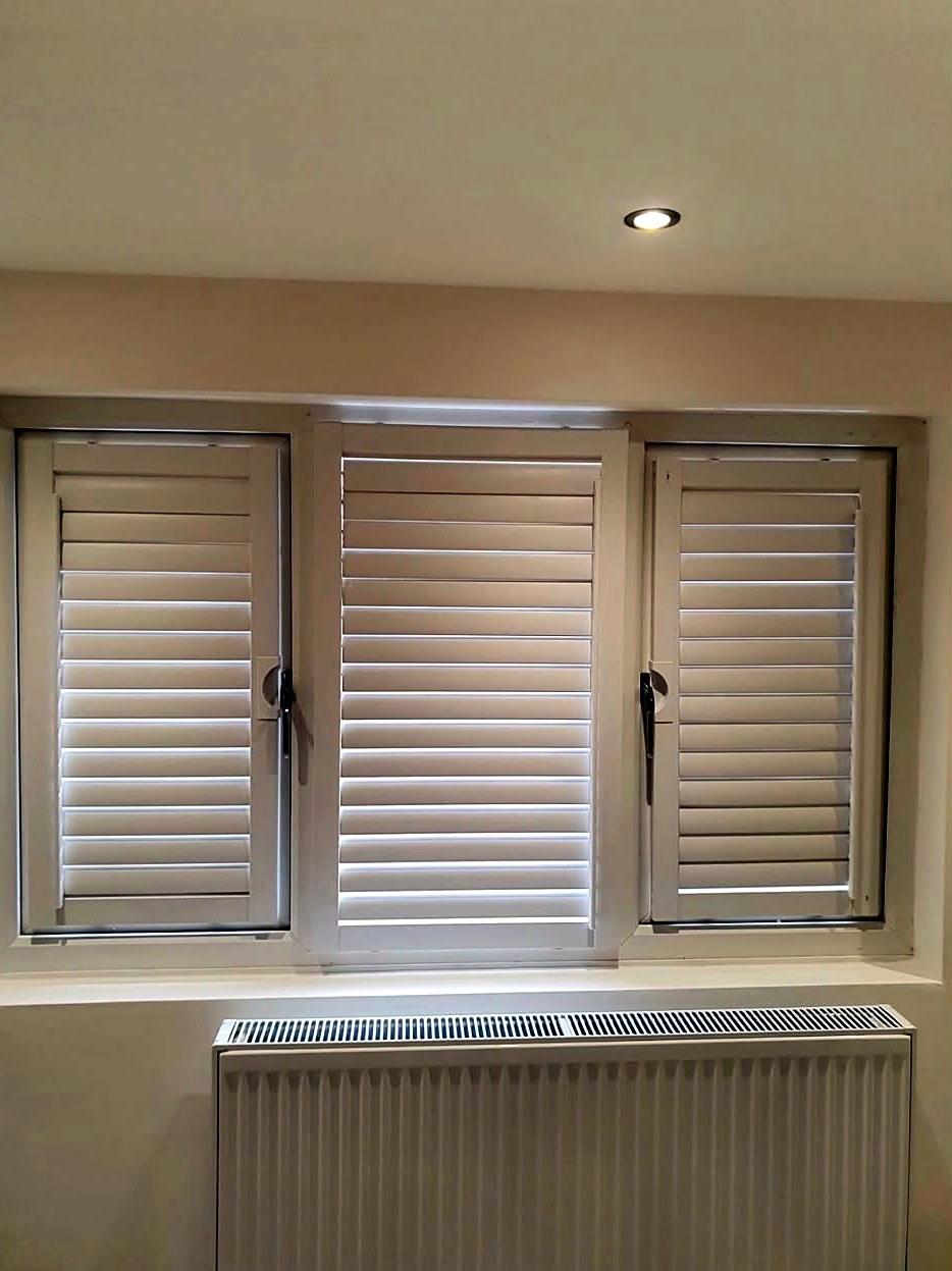 Light shutters fitted to a three-panel window above a radiator