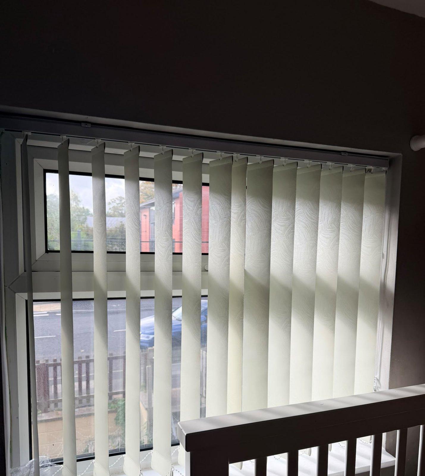 Cream vertical blinds on a landing window above the stairs