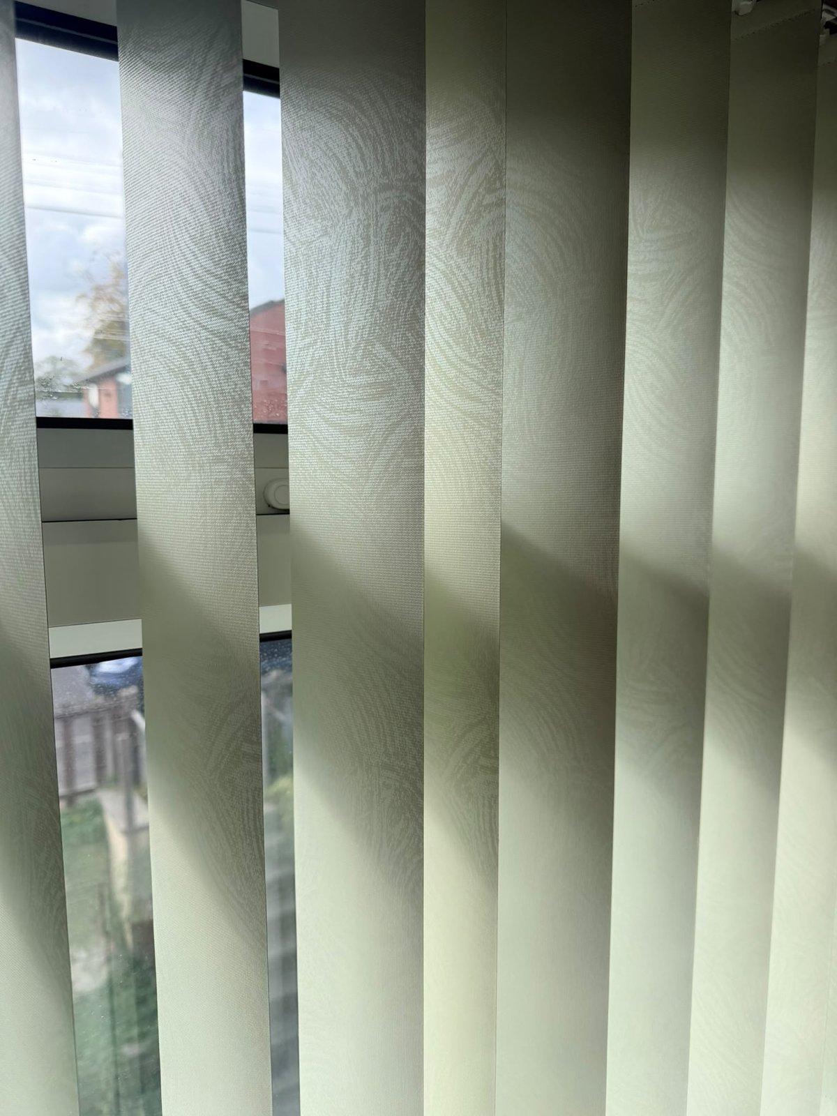 Close view of pale green textured vertical louvres with daylight behind them