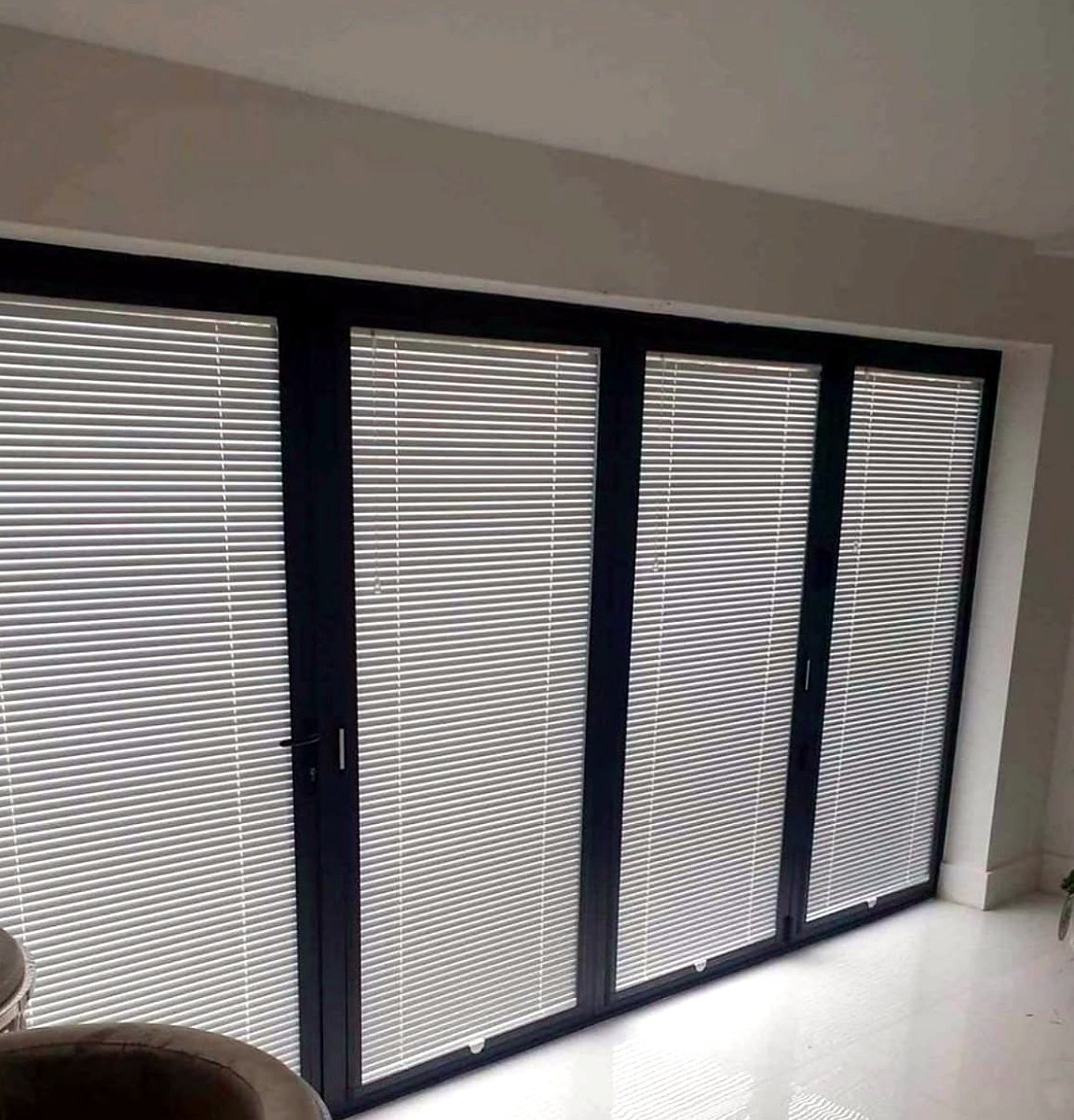 Perfect fit venetian blinds on all four panels of a dark-framed bifold door