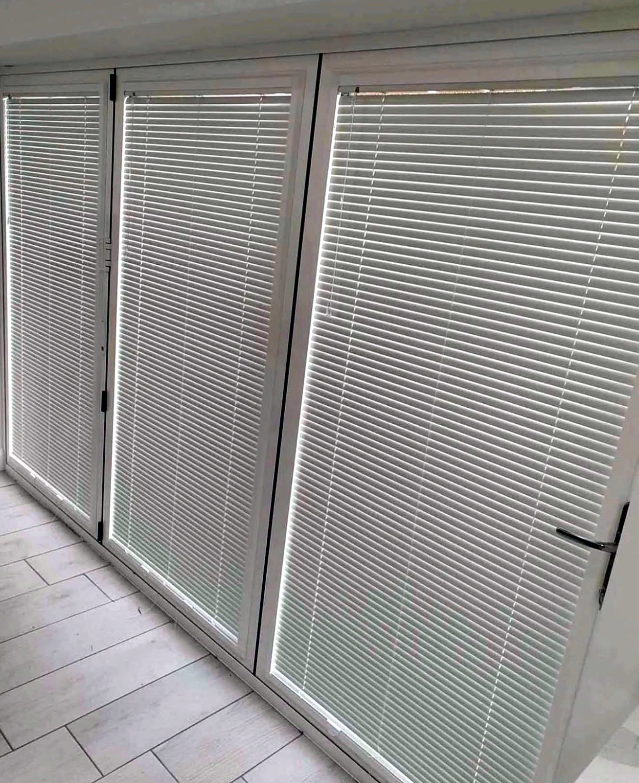 Perfect fit venetian blinds fitted to the panels of a white bifold door