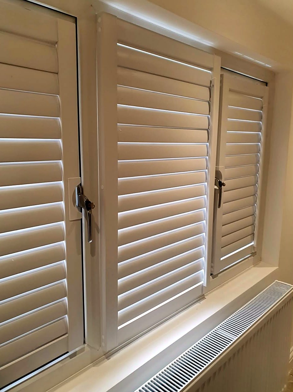 Close view of light shutters fitted inside a window recess, louvres open