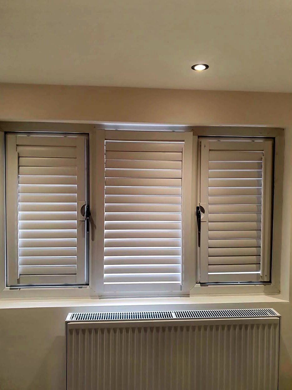 Light shutters fitted to a three-panel window above a radiator